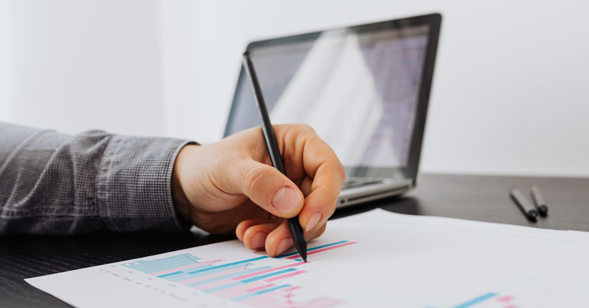 A laptop dashboard with line charts next to a coffee cup during a review meeting.