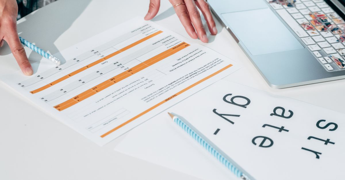 A team of three reviewing printed scorecards at a table.
